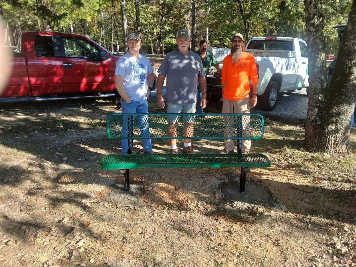 There people stand in front of bench at state park.